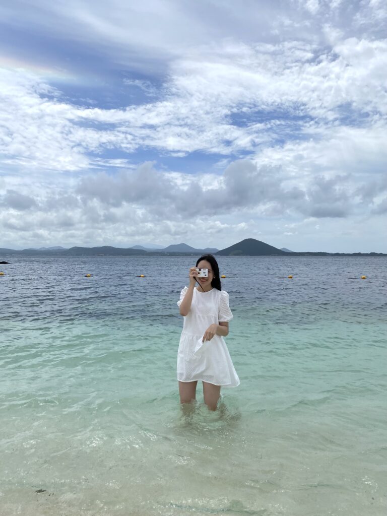 A woman at Seobinbaeksa Beach, where white coral sand meets creamy turquoise water