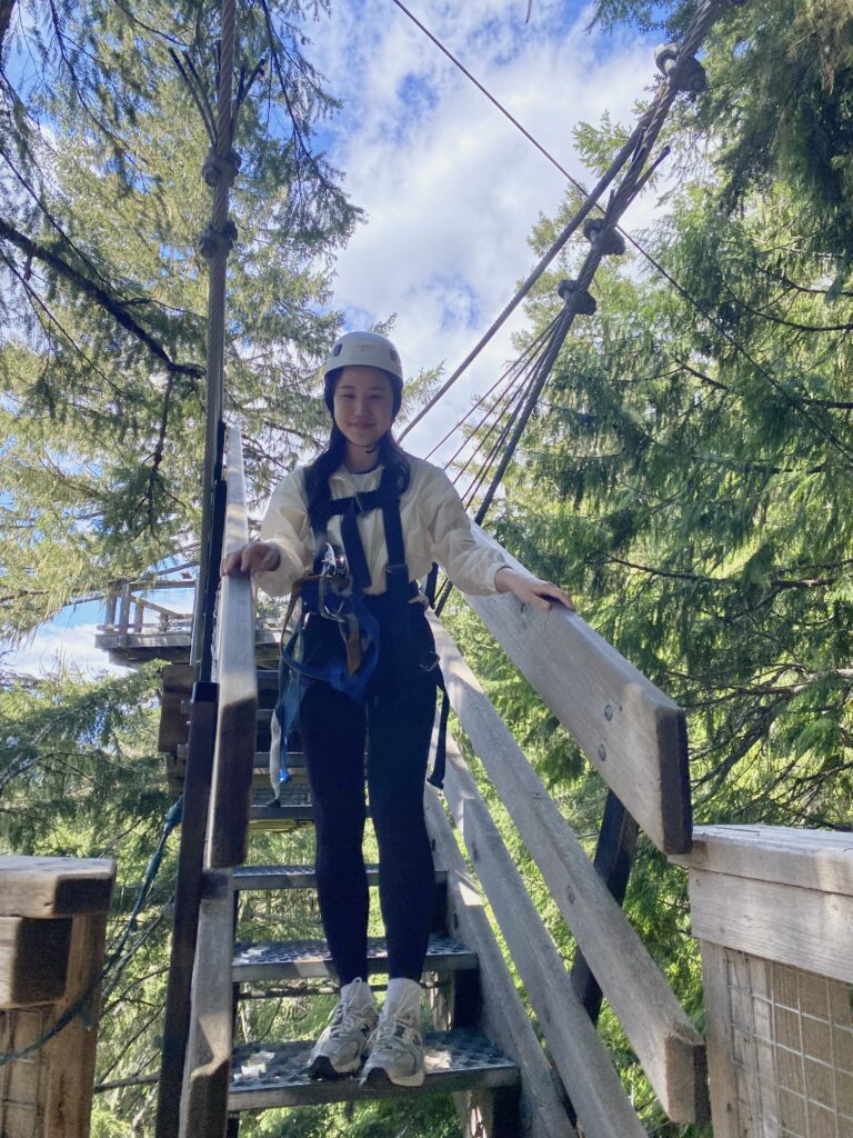 A woman in safety gear standing on a wooden platform, ready to zipline which is a classic outdoor activity