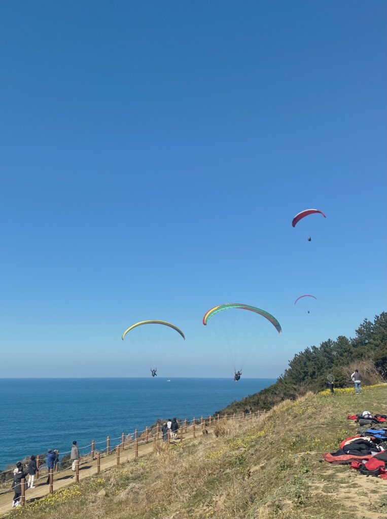 Colorful paragliders soaring above the ocean and Seoubong Peak